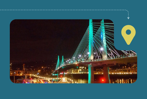 A boat passes under the Tilikum Crossing bridge at night